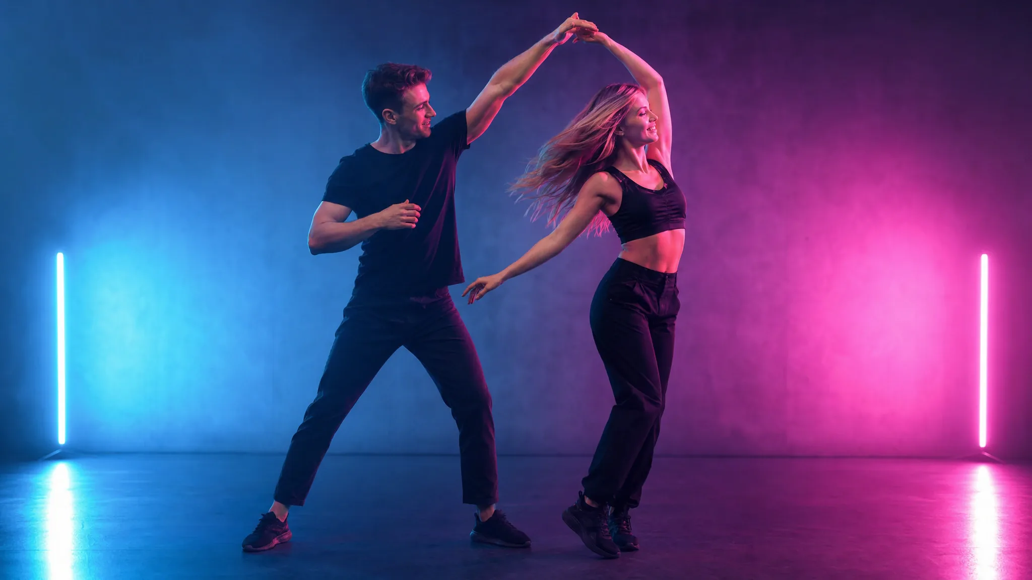 Two adults dancing a coordinated duet in a neon-lit studio