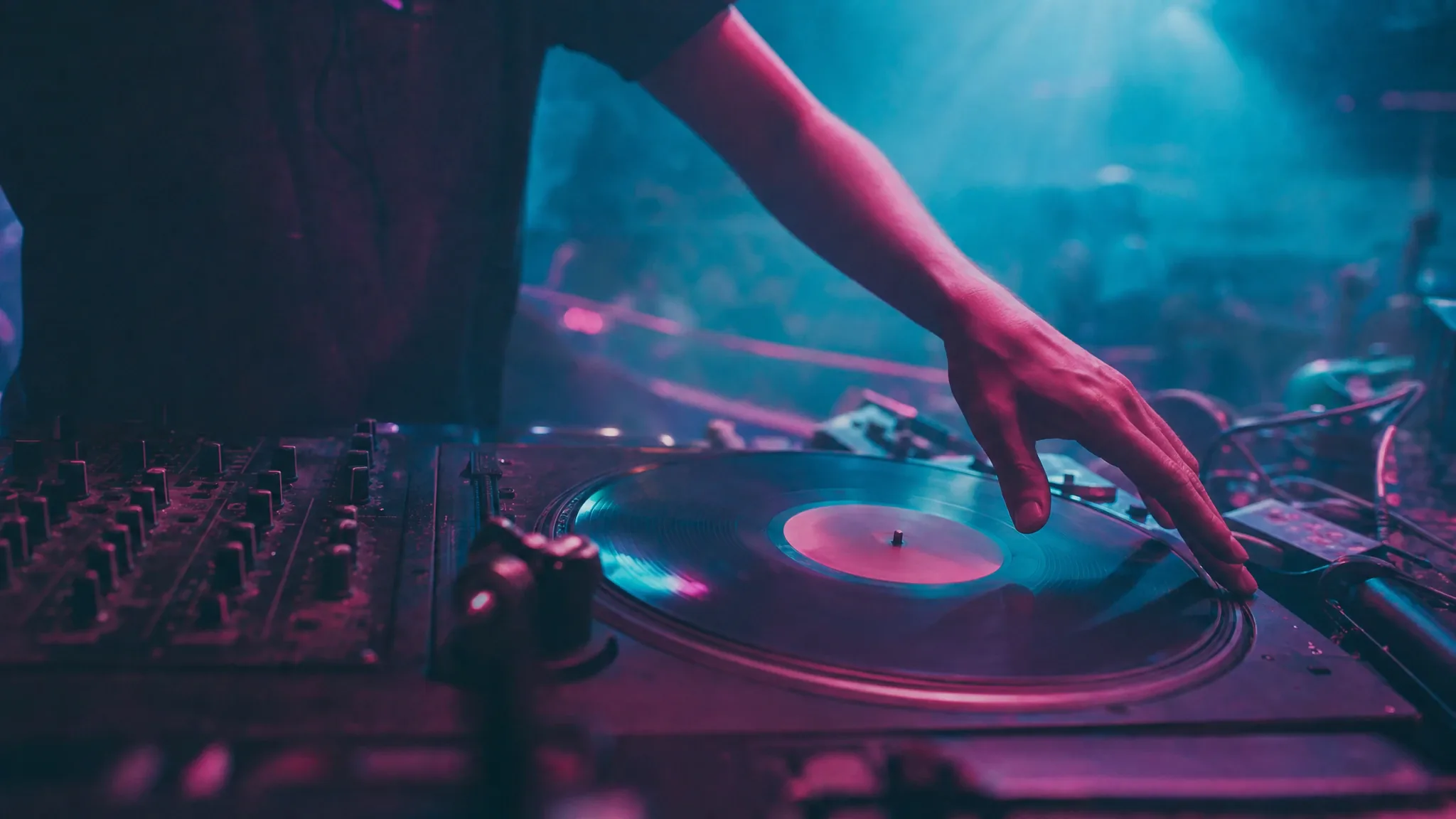 DJ booth with vinyl records and magenta and cyan club lighting
