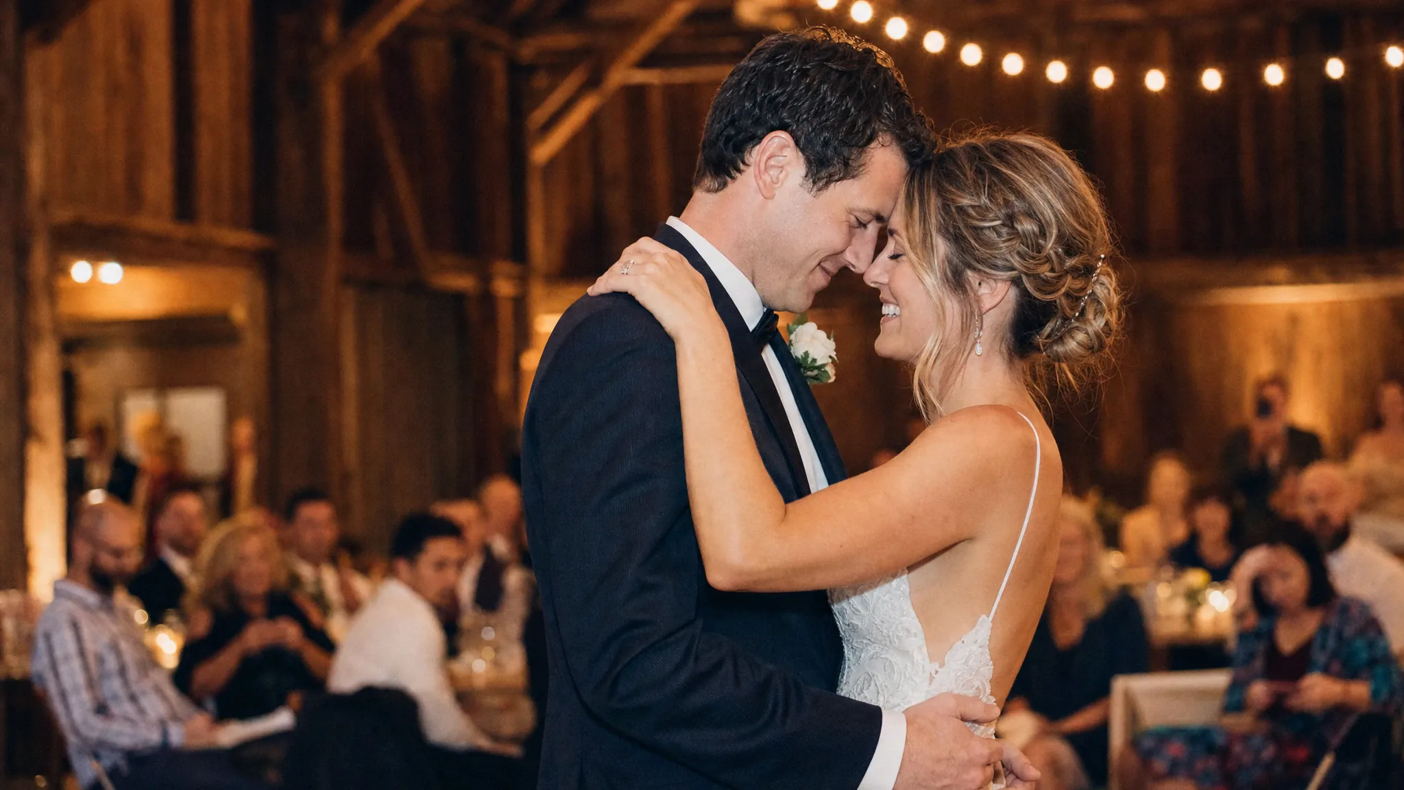 Newlywed couple sharing a first dance under warm string lights
